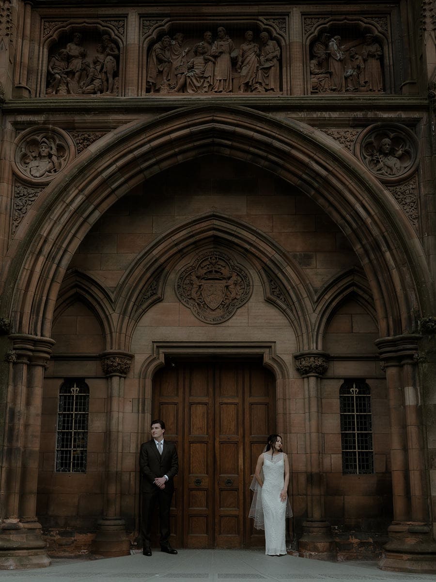 Weddings at the Royal College of Physicians Edinburgh: everything you need to know 17 Bride and groom standing beneath the ornate Gothic entrance of the Scottish National Portrait Gallery Edinburgh after their RCPE elopement