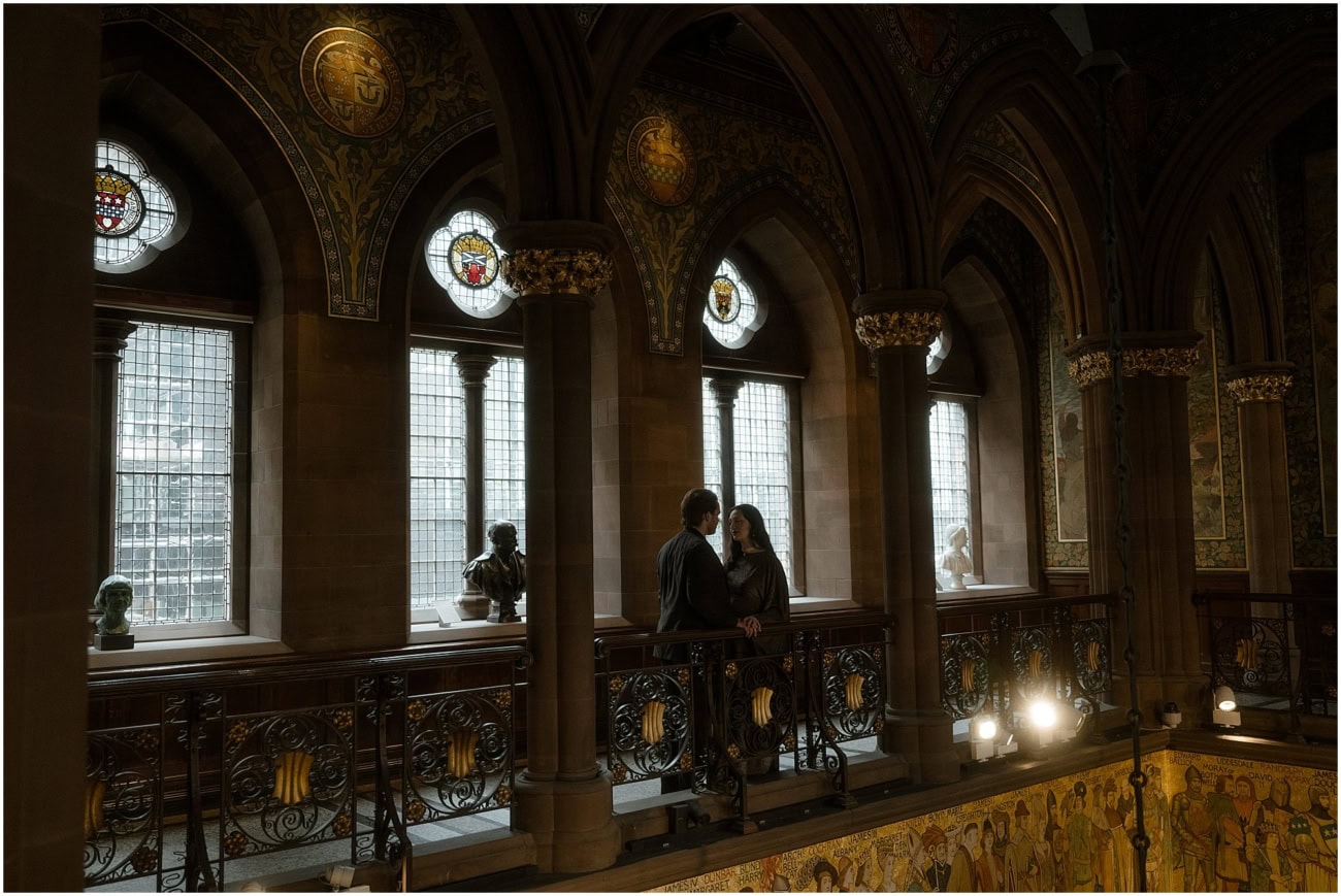 Couple facing each other on the mezzanine balcony of the Scottish National Portrait Gallery Edinburgh surrounded by stained glass and historic murals