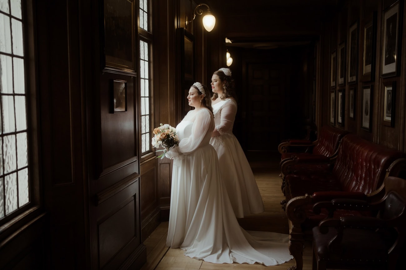 Weddings at the Royal College of Physicians Edinburgh: everything you need to know 2 Two brides standing by leaded windows in the corridor at the Royal College of Physicians Edinburgh